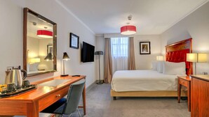 Una habitación de hotel con cama, escritorio, silla y un espejo grande.