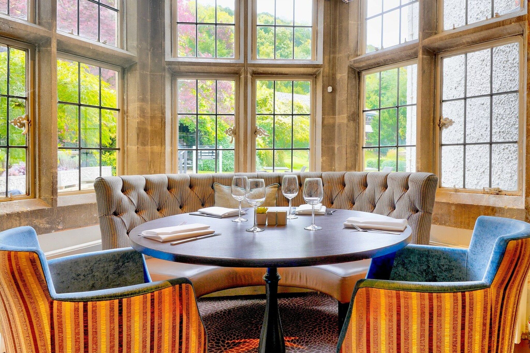 A round table with six chairs, a bench, and a dining setup with wine glasses and cutlery.