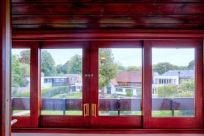 A wooden-framed window with a view of residential houses and greenery.