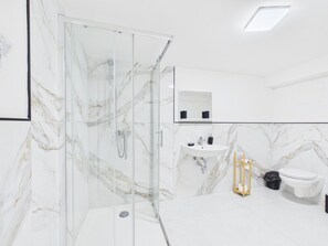 Une salle de bain moderne avec une douche à parois de verre, un lavabo et des toilettes.