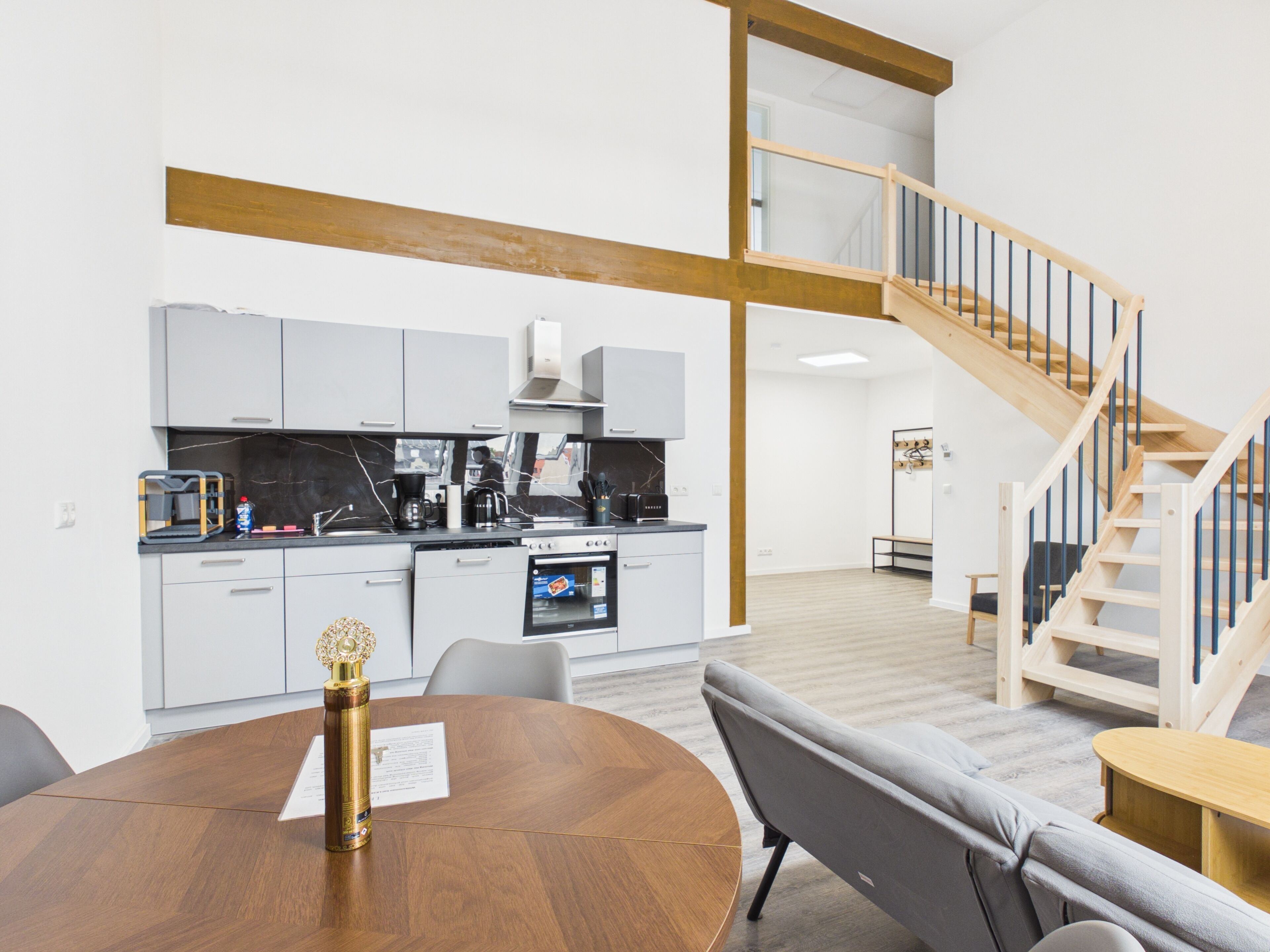 A modern kitchen with grey cabinets, a built-in oven, and a coffee maker.