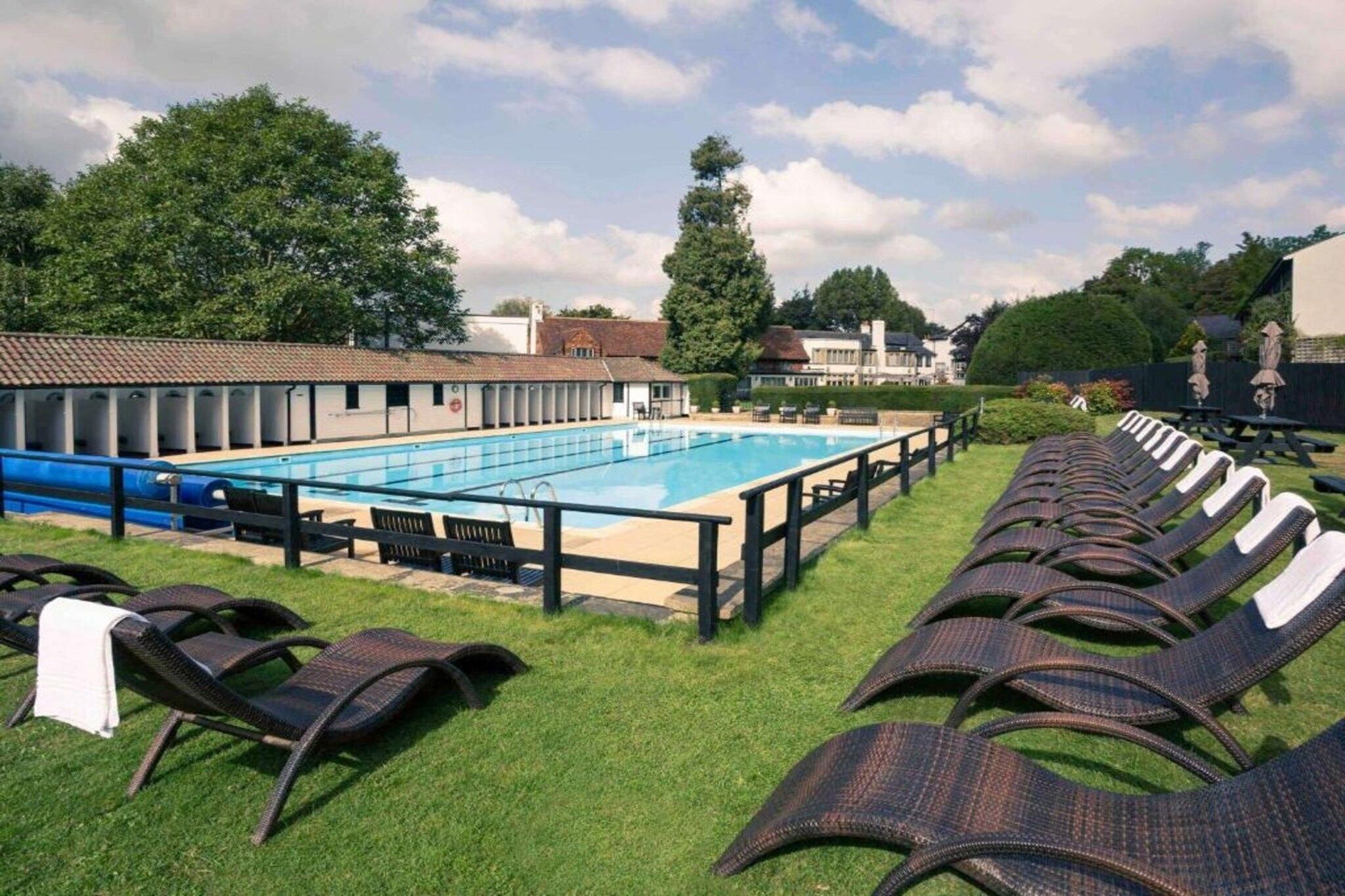 A swimming pool with lounge chairs and a covered seating area.