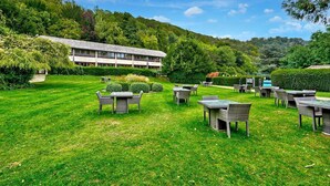 Un hotel con terraza al aire libre, rodeado de vegetación exuberante y colinas.