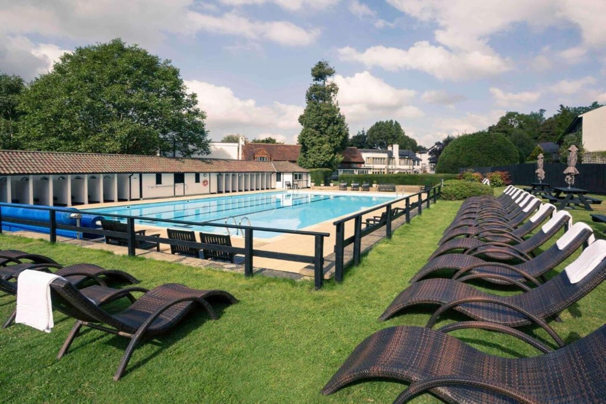 Ein Schwimmbad mit Liegestühlen und einem Gebäude im Hintergrund.