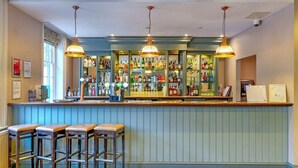 A bar area with stools, a counter with bottles, and hanging lights. - Superior Double Room (London)