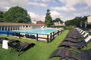 A swimming pool with lounge chairs and a building in the background.