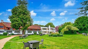 A spacious outdoor area with a paved walkway, outdoor seating, and a large tree. - Sunday Box Hill Burford Bridge - Classic Twin Room (London)