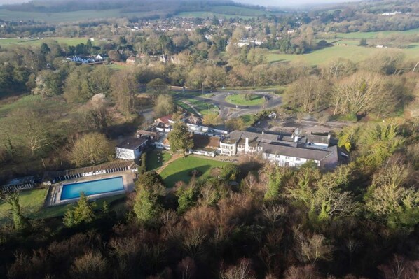A large estate with a swimming pool, multiple buildings, and a winding road.