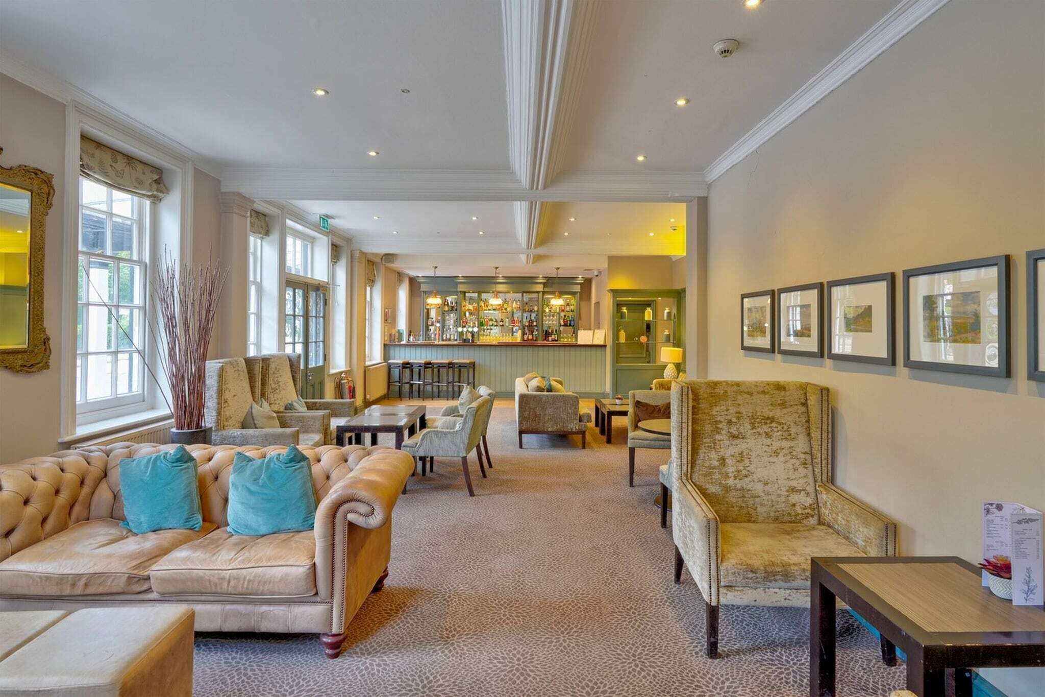 A hotel lobby with a bar, seating area, and framed artwork on the walls.