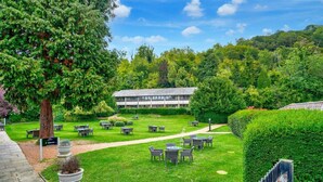 A courtyard with outdoor seating, a building in the background, and a pathway leading to the building. - Sunday Box Hill Burford Bridge - Classic Twin Room (London)