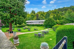 Un patio con mesas al aire libre, un edificio al fondo y un sendero que lleva al edificio.
