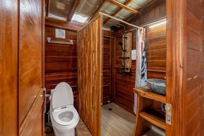 Ein Badezimmer einer Holzhütte mit Toilette, Dusche und Waschbecken.
