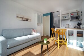 Ein modernes Wohnzimmer mit einem grauen Sofa, einem kleinen runden Tisch mit einer Pflanze und einem gelben Sessel.