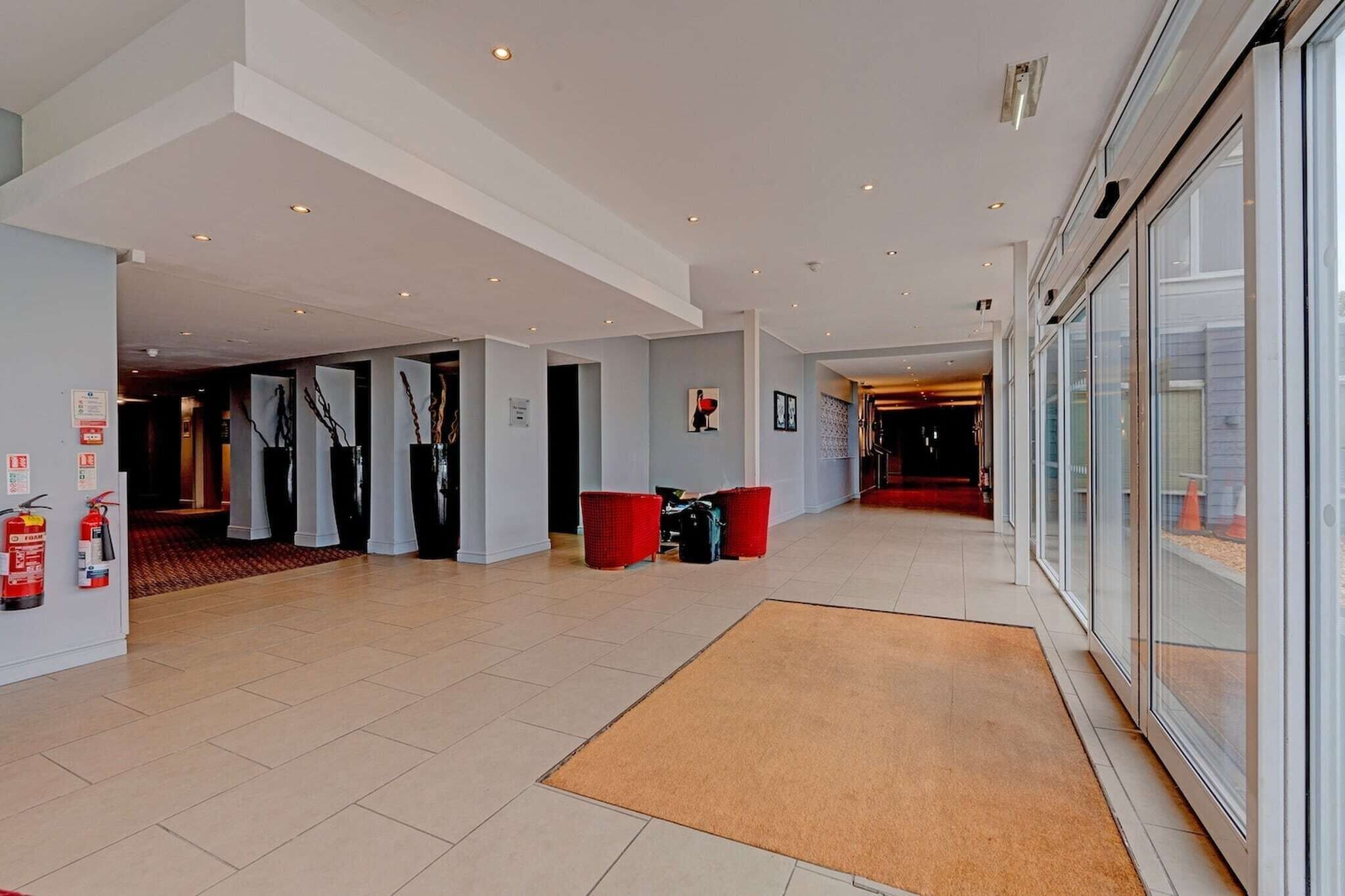 En moderne hotellobby med tydelig gangsti, brandslukker og glasvæg.