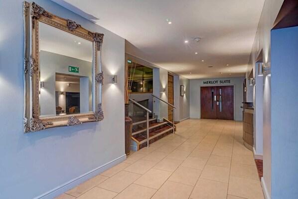 A hotel hallway with a large ornate mirror, a staircase, and a sign for the Merlot Suite.