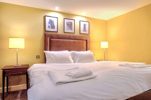 Une chambre d’hôtel avec un grand lit, deux lampes de chevet et trois tableaux encadrés accrochés au mur.