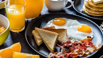 Ein Frühstücksteller mit Eiern, Speck, Toast und Orangenscheiben.