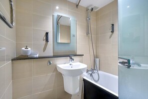 Een moderne badkamer met een wastafel, spiegel, toiletpapier, douche en bad.