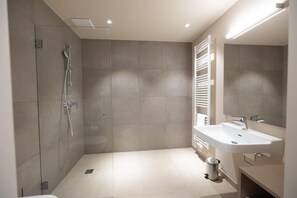 A modern bathroom with a glass-enclosed shower, a white sink, and a towel rack.