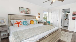 A bedroom with a wooden headboard, a bed with a quilted mattress, a nightstand with a lamp, and a view of the bathroom. - Family-Friendly Condo | Pools, Beach Walkable | Discounted Kayaks, Parasailing (Orange Beach)