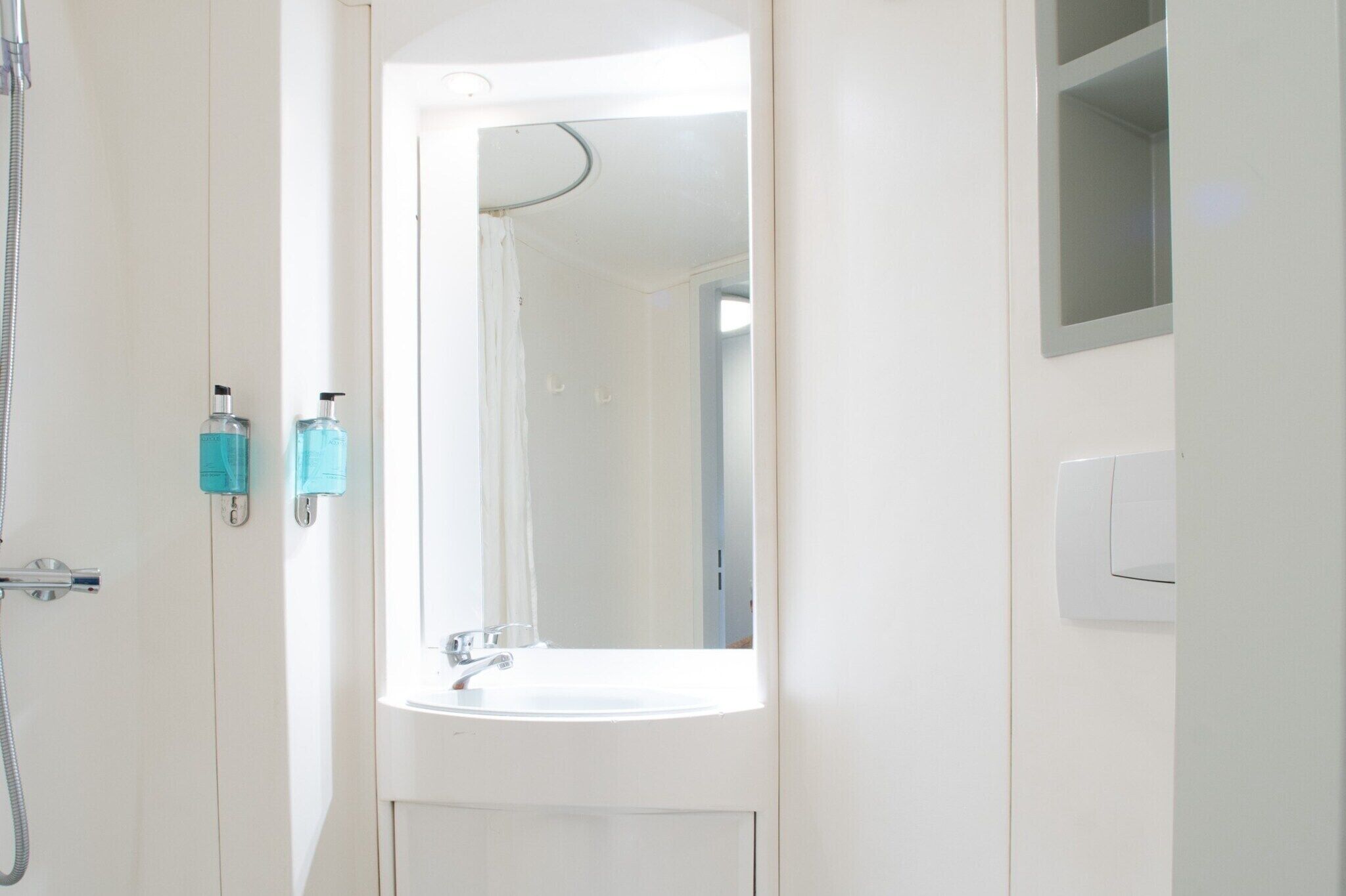 A bathroom with a sink, a mirror, and a shower.