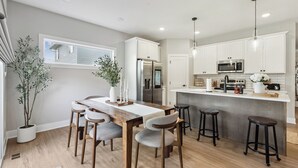 Eine moderne Küche mit einem Holztisch, Barhocker und integrierten Geräten.