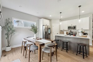Eine moderne Küche mit einem Holztisch, Barhocker und integrierten Geräten.