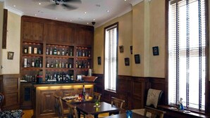 Angolo bar con scaffali in legno, bancone e sala da pranzo con sedie e tavolo.