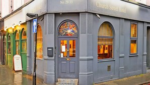 Un edificio ad angolo con un cartello che recita 'Church Street Hotel' e una porta con un'apertura al di sopra.