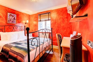 A room with a bed, a chair, a heater, a window with blinds, and a wall-mounted TV.
