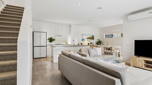 Eine moderne Wohnung mit Treppe, Wohnbereich mit Sofa, Essbereich und Küche.