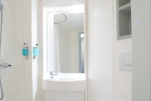 Un baño con lavamanos, espejo y ducha.