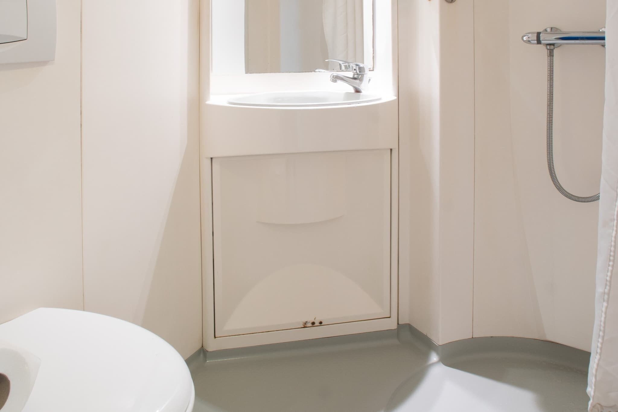 A bathroom with a white sink, a mirror, and a shower.