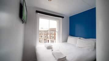Een hotelkamer met een bed, een raam en uitzicht op gebouwen.
