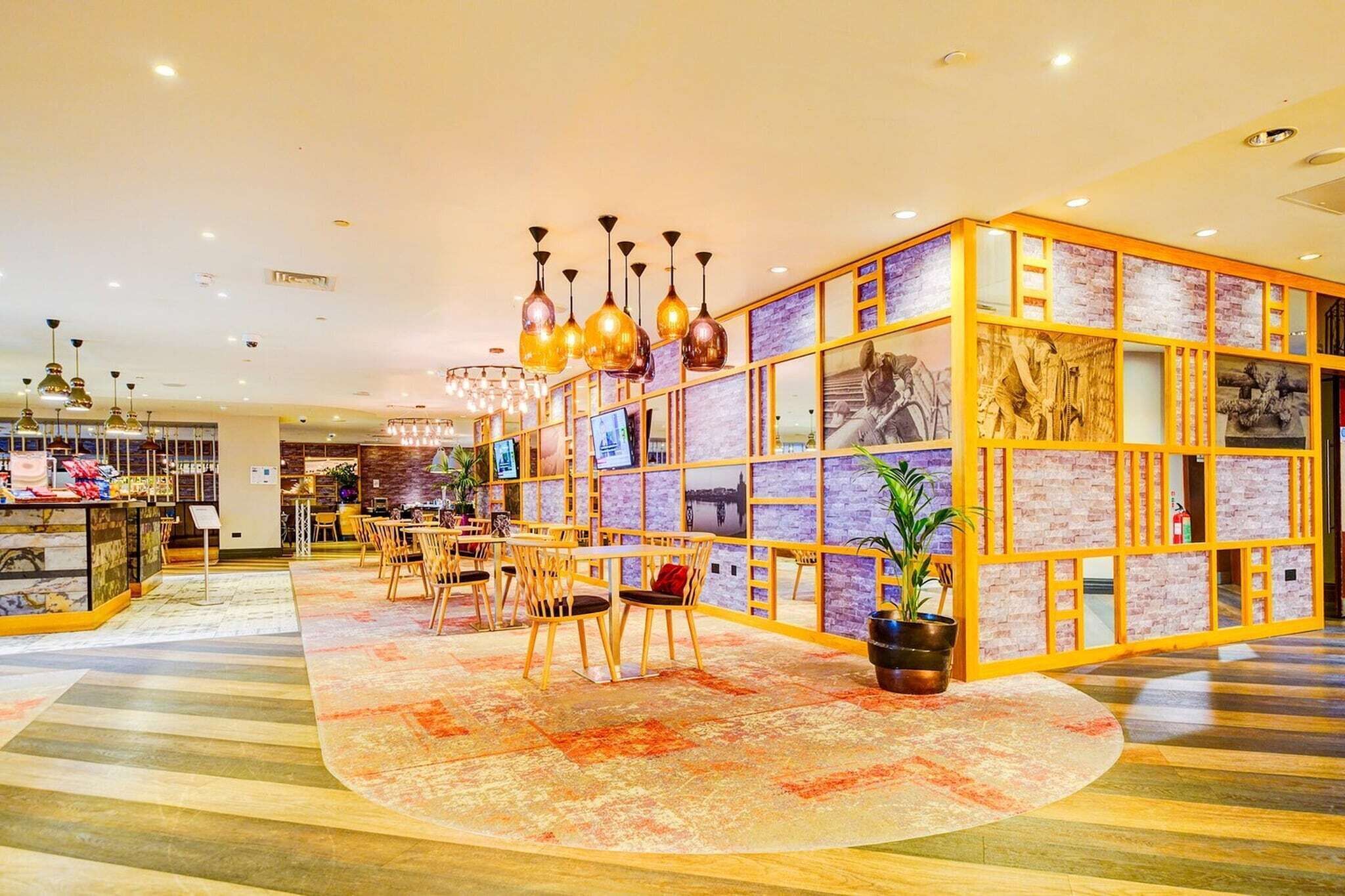 A hotel lobby with a central seating area, a reception desk, and a decorative wall with framed pictures.