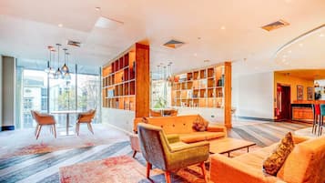 A modern lobby with a seating area, a bookshelf, and a view of the outside.