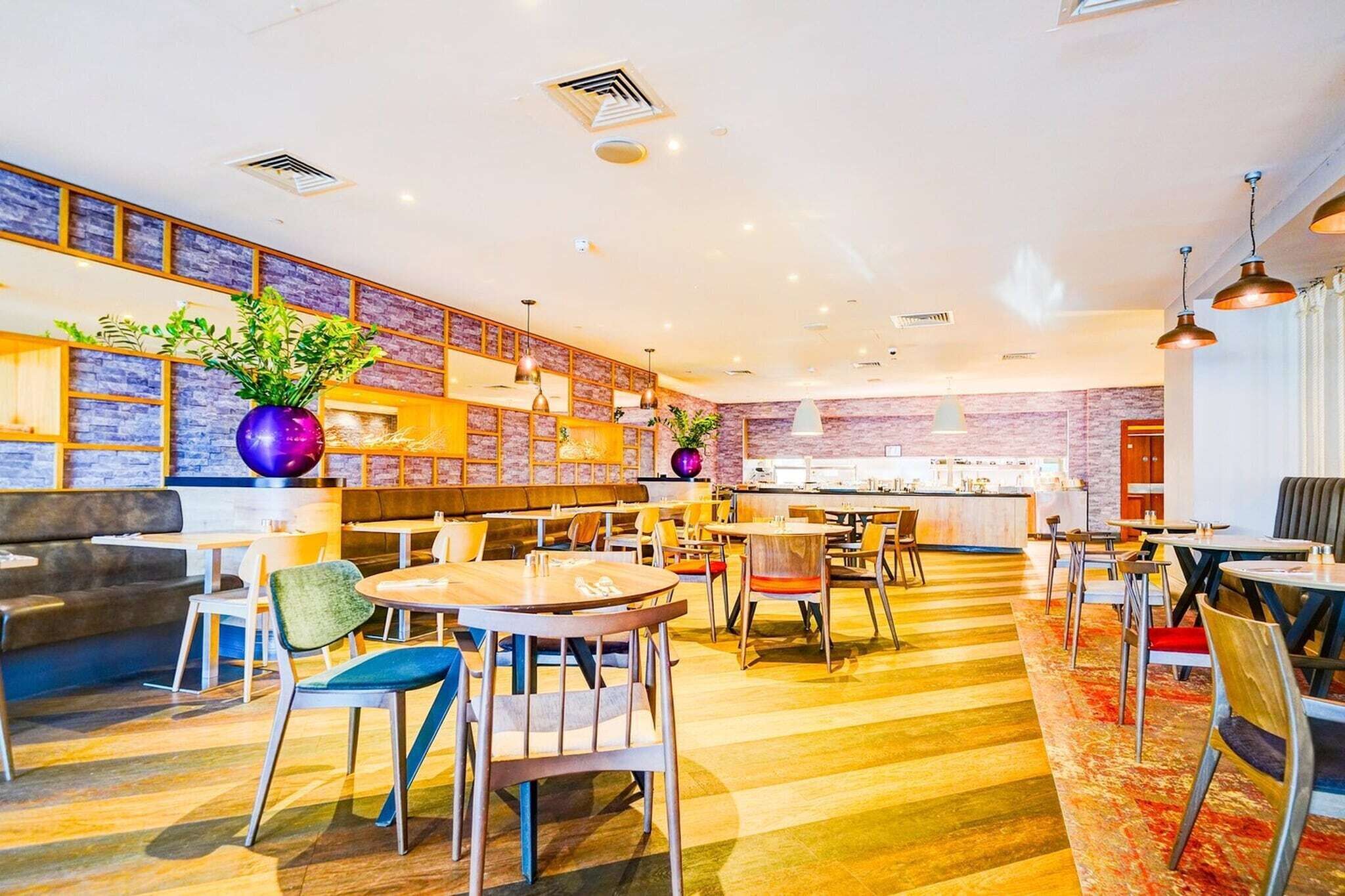 Eine moderne Hotelhalle mit Sitzbereichen, einer Bar und dekorativen Pflanzen.