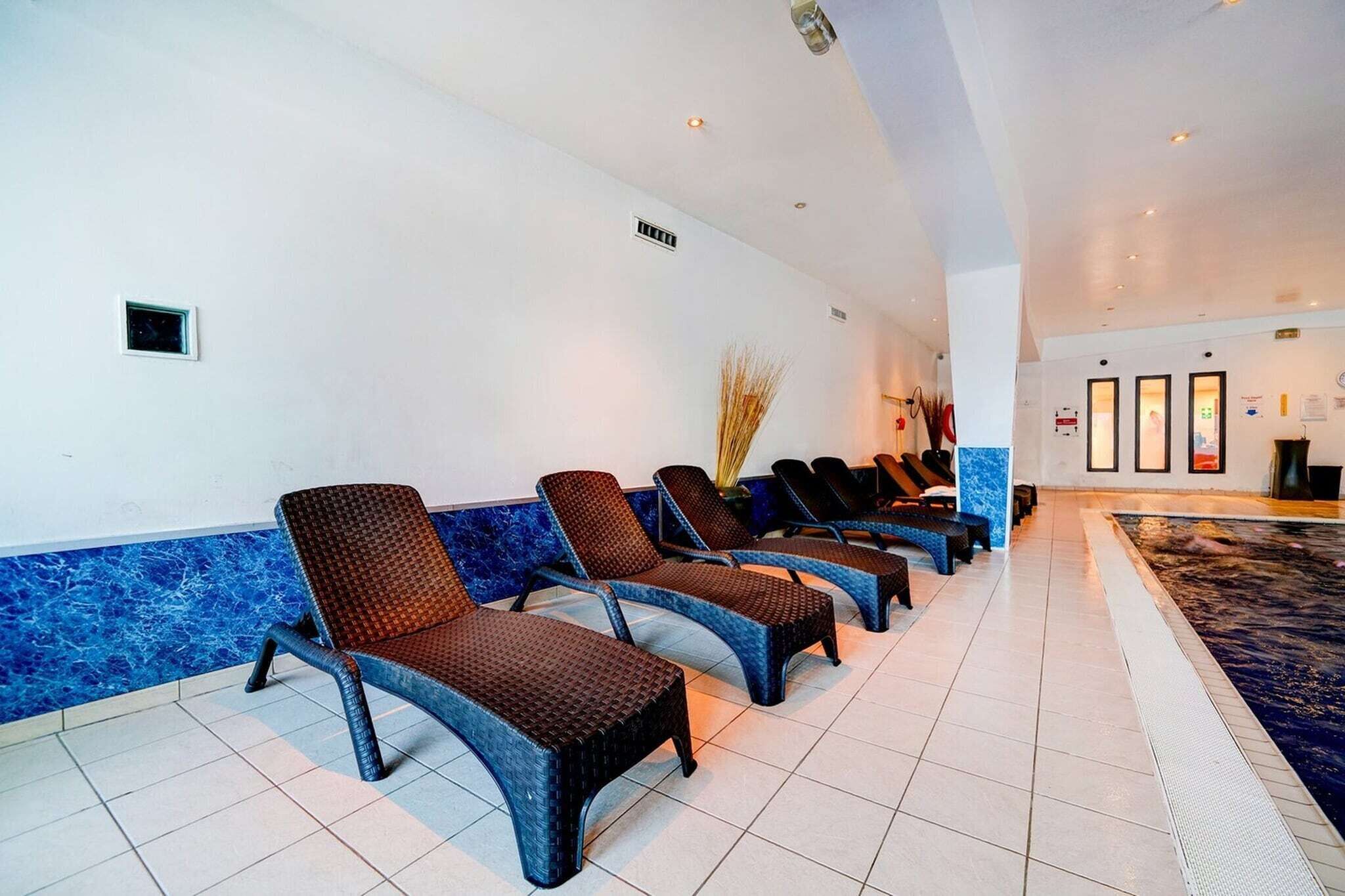 A hotel lobby with a row of lounge chairs, a reception desk, and a pool area.