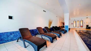 A hotel lobby with a row of lounge chairs, a reception desk, and a pool area.