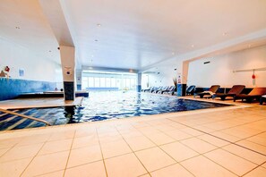 An indoor swimming pool with tiled floors, lounge chairs, and a clear view of the pool area. - Privilege Room with Panoramic Views across thecity (Cardiff)