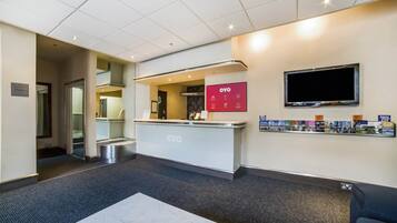 A reception area with a counter, a television mounted on the wall, and a display of products on the wall.