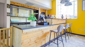 Una zona de bar con mostrador de madera, taburetes, una planta en maceta y un ventanal con vistas.