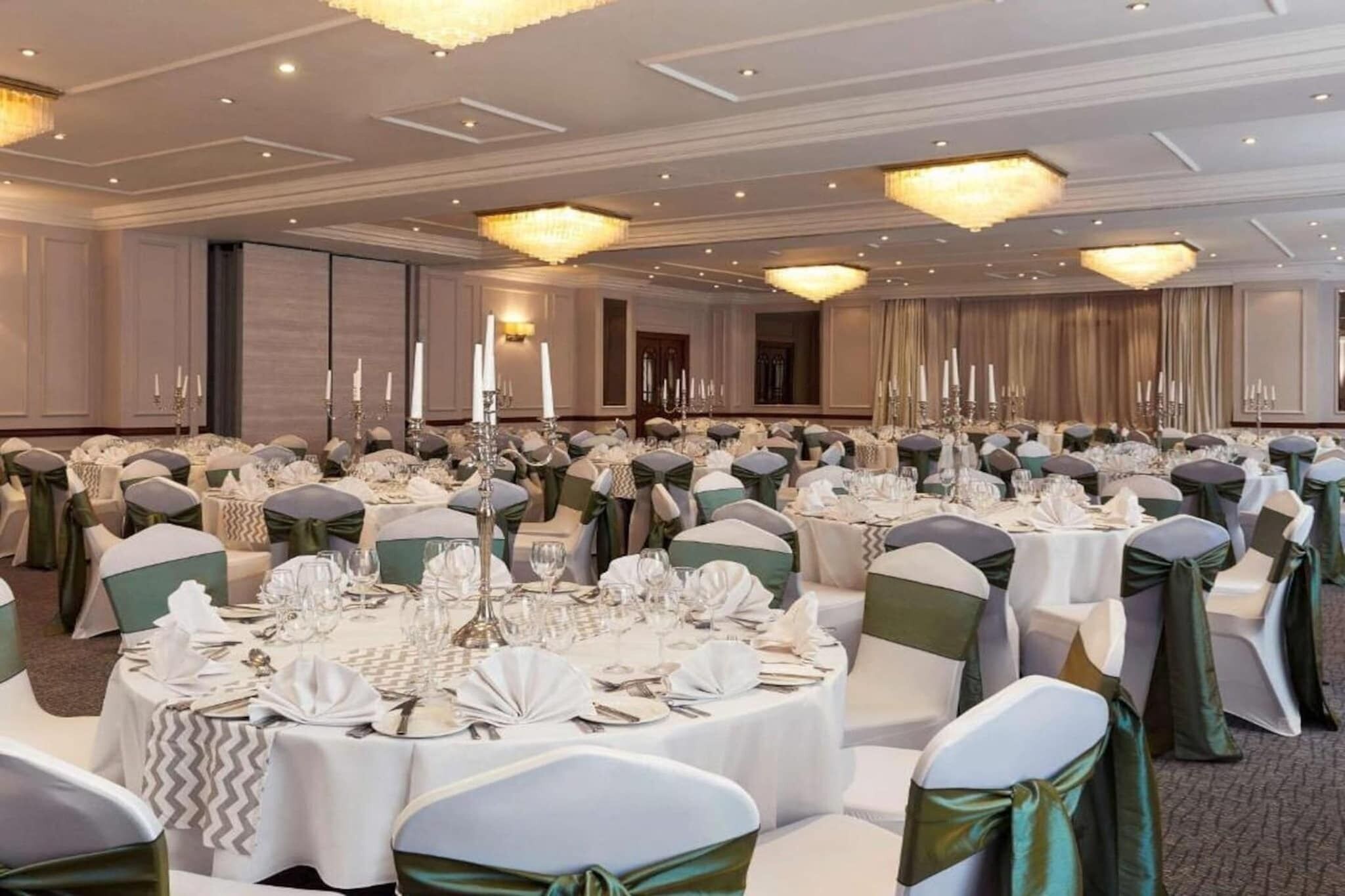 A banquet hall with round tables, chairs, and candle centerpieces.