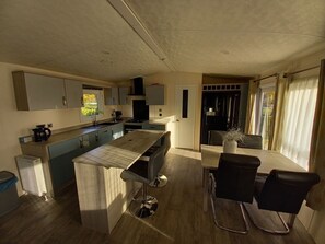 Una cocina moderna con una isla central, un área de comedor con mesa y sillas, y vistas al exterior a través de una ventana.