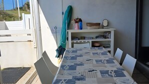 A dining area with a table set for four, a white cabinet with various items, and a view of the outside.