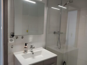 Ein modernes Badezimmer mit Waschbecken, Spiegel, Dusche und Toilette.