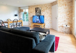Un salon avec un canapé, un téléviseur et un mur en pierre.