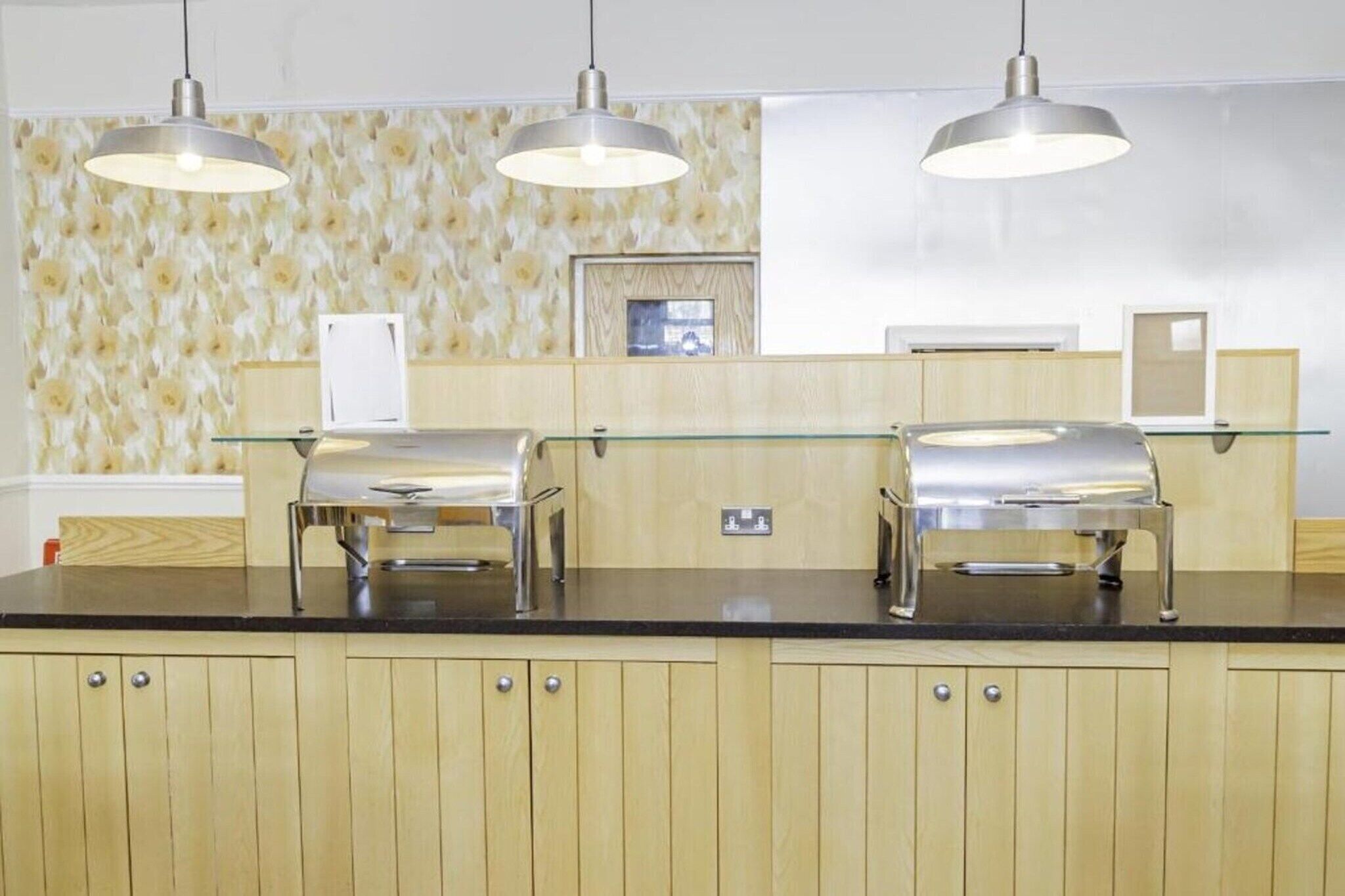 Una cocina moderna con armarios de madera, encimera de vidrio y electrodomésticos de acero inoxidable.