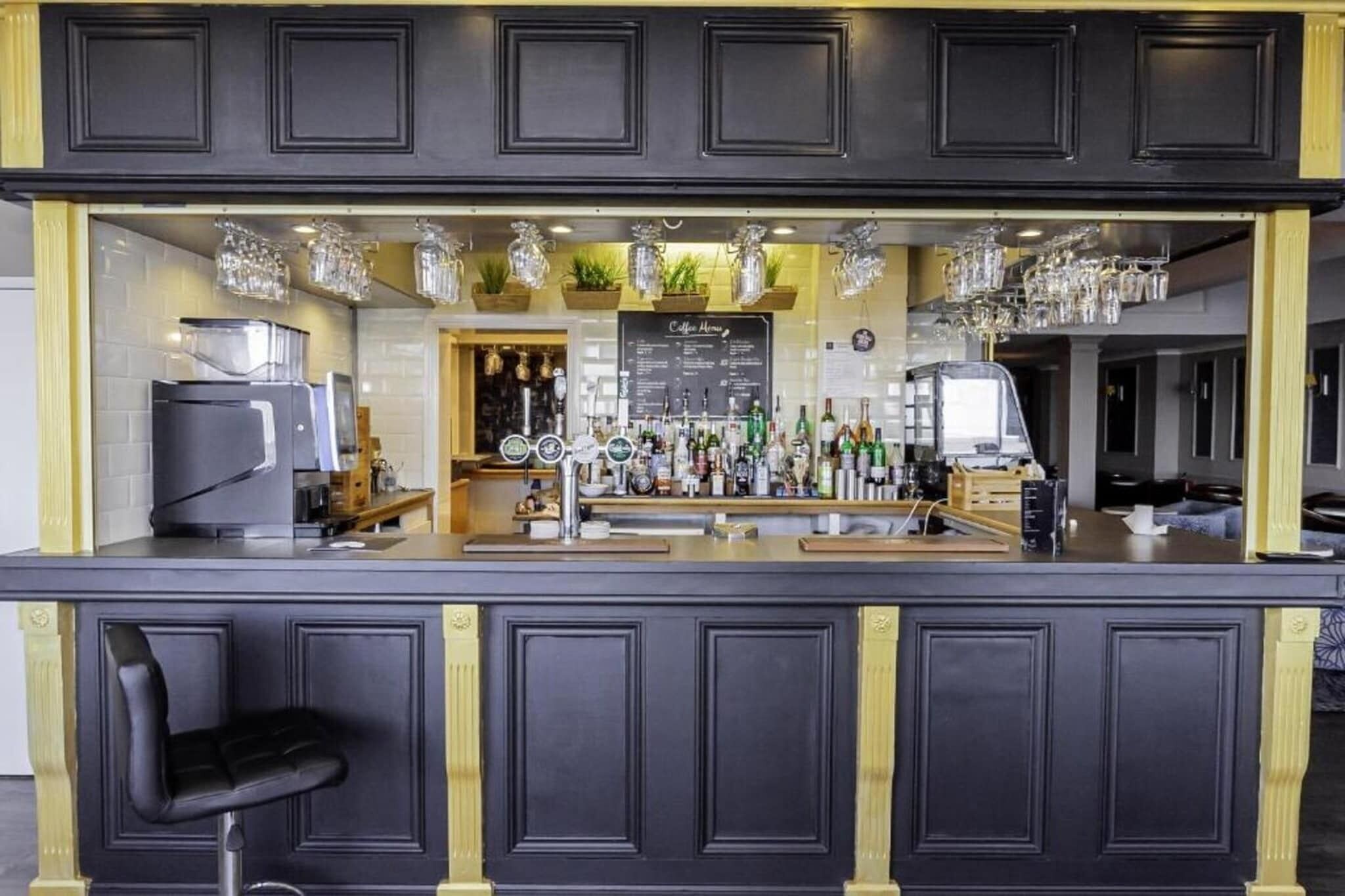 Eine Bar mit einer Theke, Hockstühlen und einer Speisekarte.