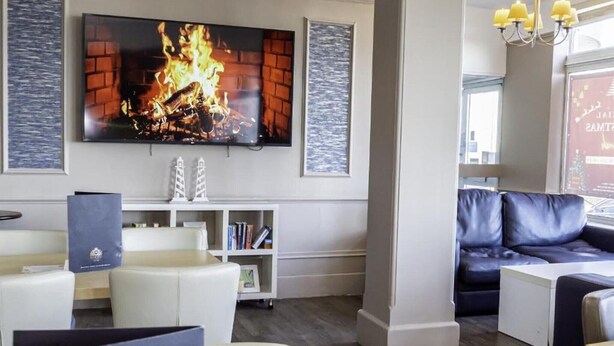 Un vestíbulo moderno con chimenea, un televisor de pantalla plana, un sofá y una estantería.